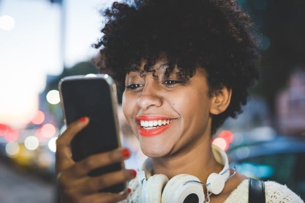 une femme souriant devant son téléphone 