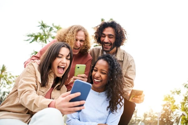 jeunes gens souriants devant leur portable 