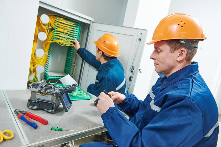 Deux techniciens raccordant une fibre optique dans un boîtier d'épissure
